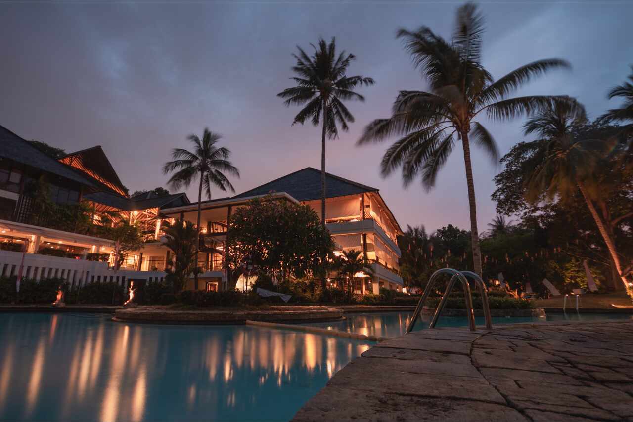 Background of a high-end hotel with palm trees and a pristine pool area, set in a tropical paradise.